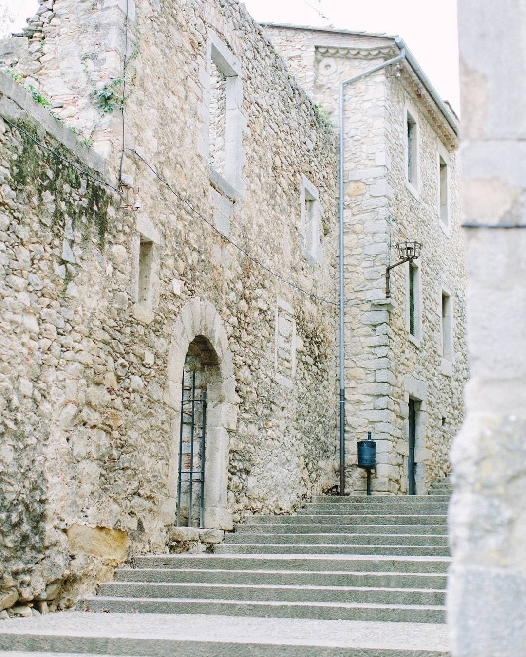 Auto-generated description: A stone building with an arched doorway is situated next to a flight of stone steps.