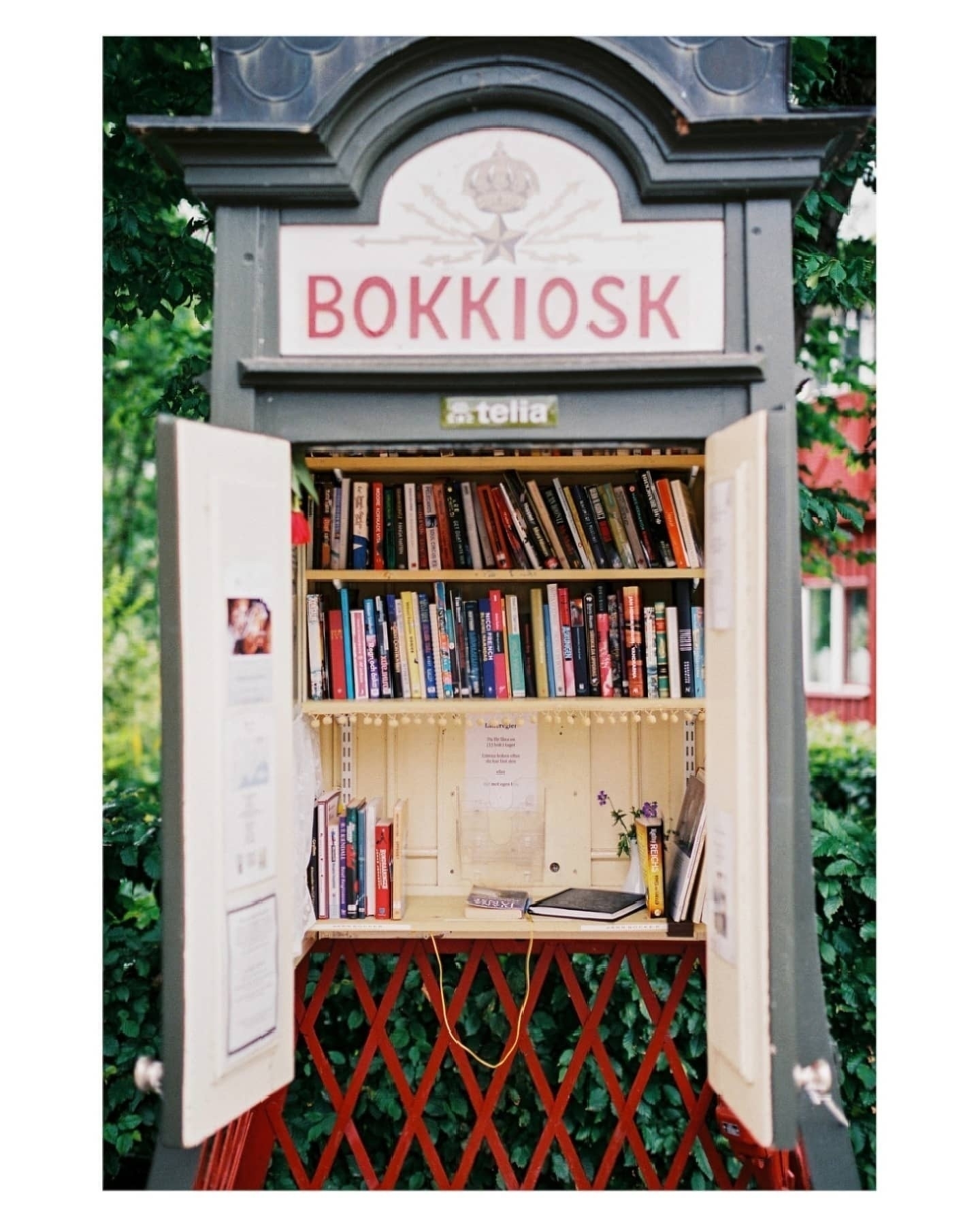 Auto-generated description: A converted phone booth serves as a small public library filled with books and labeled Bokkiosk.