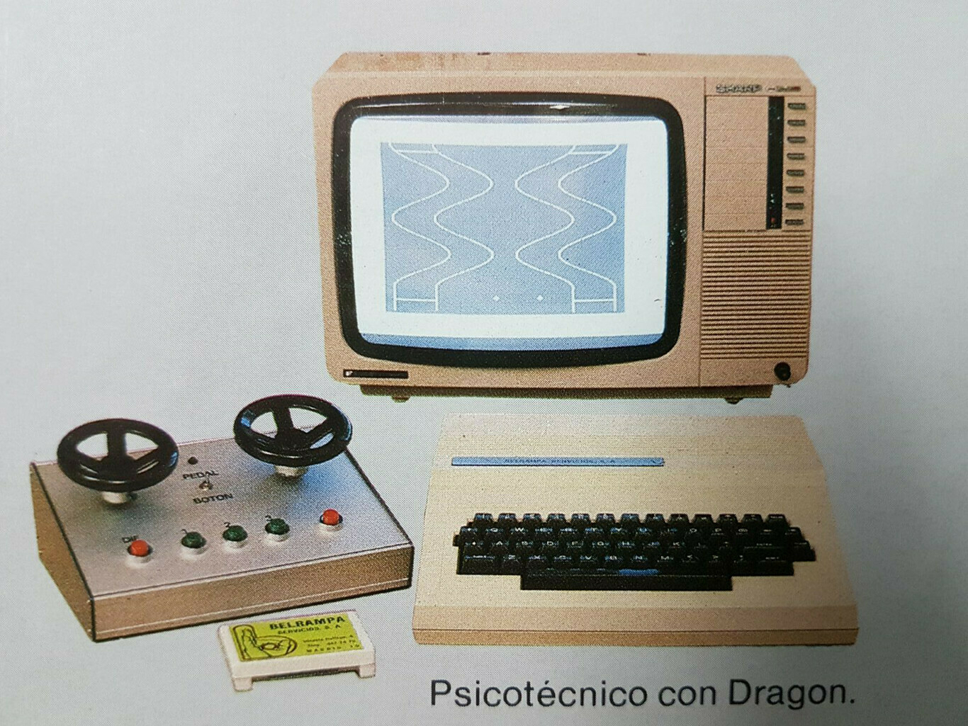 A vintage computer setup from the 1980s, used for driving aptitude tests in Spain. A small CRT monitor displays a simple blue and white video game with wavy parallel lines. Below and to the left of the screen is a metal control box with two steering-wheels. To the right of the controller is a keyboard.
